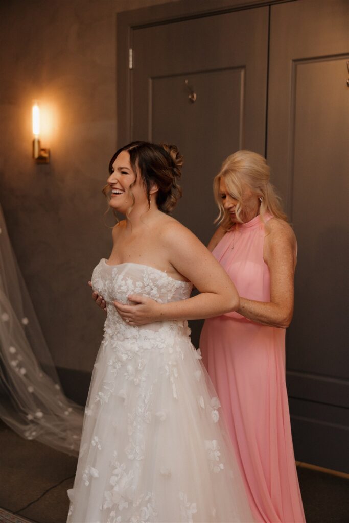 mother of the bride helping her with her wedding dress