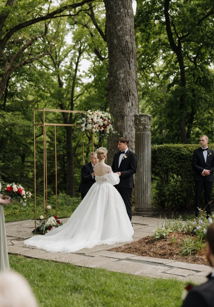 cute picture of the bride and groom holding hands during their ceremony