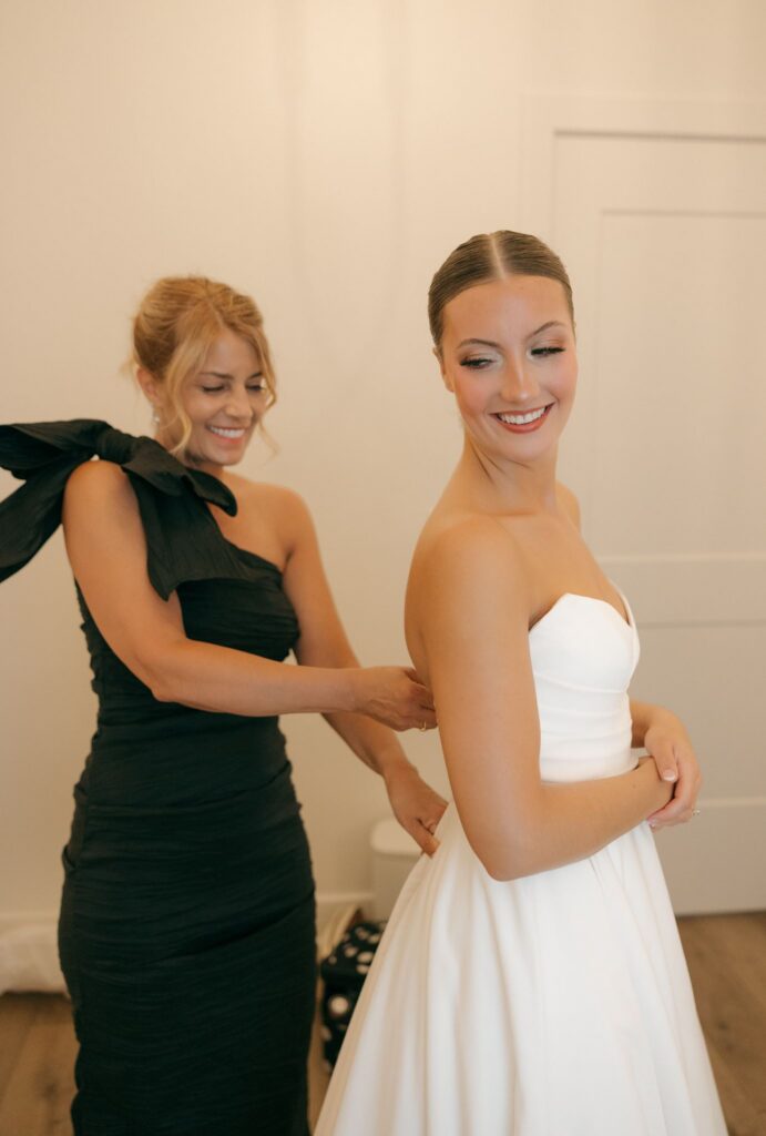 mother of the bride helping her with the wedding dress